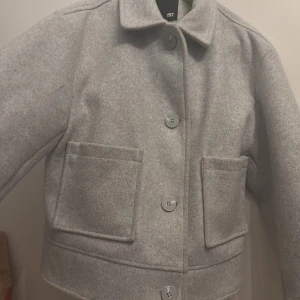 Grå kappa med knappar - Säljer en stilren grå kappa med stora knappar och två framfickor. Jätte fin nu till våren! Storlek S men passar som M o Xs oxå