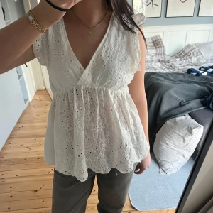 Vit blus med spetsdetaljer - Säljer en söt vit blus med v-ringning och spetsdetaljer. Blusen har volangärmar. Den är köpt secondhand 