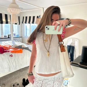 Vit och röd topp med spetsdetaljer - Säljer en söt zara vit topp med röda spetsdetaljer på ärmarna. Toppen är ärmlös och har en avslappnad passform. Perfekt för varma dagar och kan enkelt matchas med olika outfits.