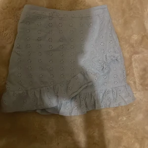 Ljusblå kjol från Primark - Söt ljusblå kjol från Primark med broderade blommor och volangdetalj längst ner. Perfekt för sommarens varma dagar! Kjolen har en elastisk midja för extra komfort. Passar bra till både vardag och festliga tillfällen.❤️