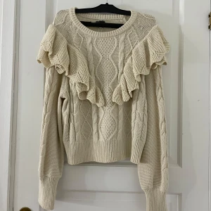 Beige stickad tröja från ONLY - Säljer en superfin beige stickad tröja från ONLY. Den har volangdetaljer på axlarna och ett snyggt flätmönster. Tröjan är i storlek L men skulle vilja säg att den är mer en M/S. Aldrig använd då jag inte haft något tillfälle att använda den. 