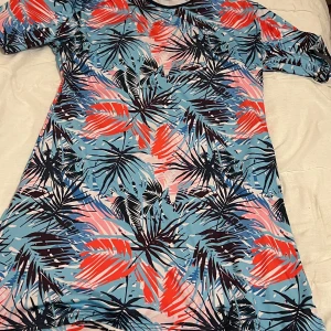 Färgglad baddräkt från Argisa - Säljer en superfin baddräkt från Argisa i storlek 48. Den har ett tropiskt mönster i blått, rött och svart med korta ärmar. Perfekt för sommarens stranddagar! Materialet är en mix av polyamid och elastan vilket gör den både bekväm och stretchig. Baddräkten är i nytt skick och redo för nya äventyr! 🌴