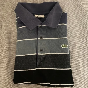 Lacoste pike - Till salu: Randig Lacoste Pike Tröja  Snygg randig pike från Lacoste i bra skick. Perfekt för både casual och sportiga tillfällen.   - Storlek: 3 - Färg: Blå - Pris: 299  Kontakta gärna vid frågor eller intresse 