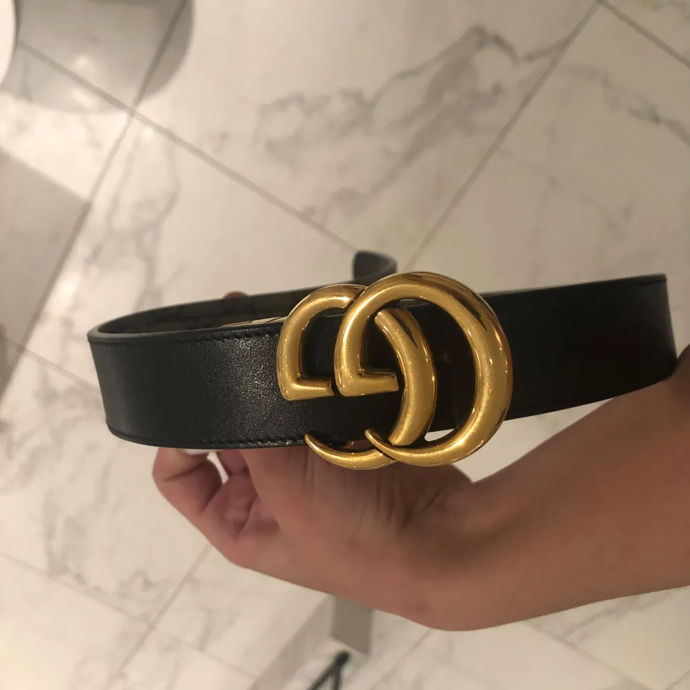 Säljer ett snyggt Gucci bälte i mycket bra skick. Det har ett klassiskt GG-spänne i guld och är gjort av svart skinn. Perfekt för att ge din outfit en lyxig touch. Passar både till vardag och fest!. Accessoarer.