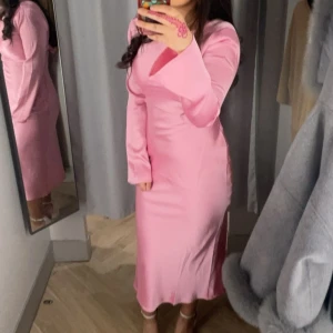 Rosa långklänning med öppen rygg - Säljer en superfin rosa långklänning i syntetmaterial. Den har en elegant öppen rygg med en söt knytning och långa ärmar. Perfekt för vårens och sommarens fester! 💖