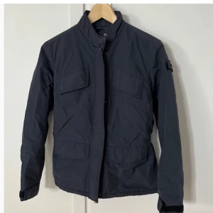 Svart jacka från ASPESI - Säljer en stilren svart jacka från ASPESI i storlek S. Jackan har en hög krage och praktiska fickor framtill. Den är tillverkad i ett slitstarkt material med bra andningsförmåga. Perfekt för höst och vår!