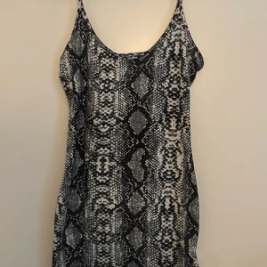 Ormmönstrad klänning - Säljer en supercool ormmönstrad klänning i svart och grått. Den är ärmlös och har en tight passform som verkligen framhäver figuren även en liten slits🐍✨