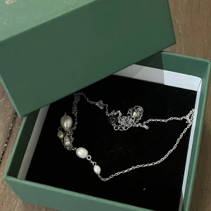 Ocean Necklace Steel - Helt nytt!!! Snyggt halsband i stål med pärldetaljer. Perfekt för att ge en elegant touch till din outfit. Halsbandet har en tunn kedja med små och stora pärlor som ger en havsinspirerad känsla. Kommer i en fin grön ask, perfekt för present eller förvaring. 