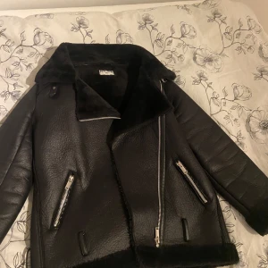 NA-KD jacka - Säljer en snygg svart skinnjacka från NA-KD med fuskpälsdetaljer. Perfekt för höst och vinter, håller dig varm och stilren. Passar både till vardags och fest! 💞