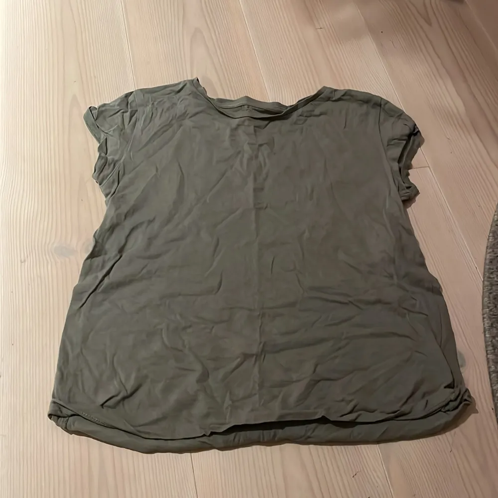 Säljer en olivgrön t-shirt från H&M i ekologisk bomull. Den är kortärmad och har en avslappnad passform, perfekt för vardagsbruk. T-shirten är i bra skick och passar till både jeans och kjol. Perfekt för en casual look! 🌿. T-shirts.