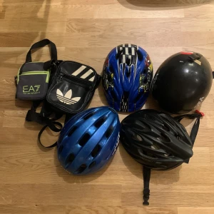 Flera cykelhjälmar i olika färger och väskor  - Säljer tre cykelhjälmar i olika färger och stilar. En blå hjälm med glansig yta, en svart hjälm med matt finish och en blå hjälm med svarta och vita ränder samt mönster. Perfekt för cykling och andra utomhusaktiviteter. Alla hjälmar är i bra skick och redo för användning. Varje hjälm och vaska kostar 20kr.