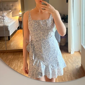 Blommig klänning från Princess Polly - Säljer en superfin blommig klänning från Princess Polly i storlek EU 40 men mer som en M/38. Den har en söt volangdetalj och knytning i midjan. Perfekt för sommardagar har en kort längd som ger en fräsch look. 🌸