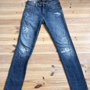 Blå Replay Anbass - Säljer ett par snygga blå jeans från Replay i modellen Anbass. De har en cool slitningseffekt och en slim passform som sitter perfekt. Perfekta för både vardag och fest! 🕺