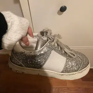 (Öppen för byte vad som)Säljer ett par snygga glittriga sneakers från Valentino. Skorna är silverfärgade med vita detaljer och har coola nitar på hälen. Perfekta för att ge din outfit lite extra bling! Passar både till vardags och fest. (Skorna har tappat en nit) 