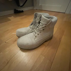 Beige boots från Whistler - Säljer ett par snygga beige boots från Whistler i bra skick. De har en mysig stickad kant upptill och snörning framtill. Perfekta för höst och vinter med sin robusta design och bekväma passform.