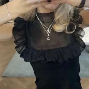 Svart topp med Volangdeatiljer - Säljer en snygg  svart topp med volangdetalijer, Den är använd bara 2 gånger, är i väldigt bra fräsch och ny skick hör gärna av dig om du är intresserad🤍💓