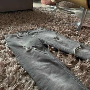 Grå jeans från Nudie Jeans - Säljer ett par grå jeans från Nudie Jeans i bra skick. De har några snygga slitningar på knäna . Perfekta för både vardag och fest! Passar till allt och är superbekväma. Nypris runt 2000 kr Hör av dig vid intresse! 