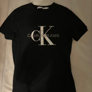 Svart t-shirt från Calvin Klein Jeans - Snygg svart t-shirt från Calvin Klein Jeans med stort CK-logotyptryck på framsidan. Perfekt för en stilren och modern look.