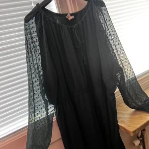 Grön klänning från Divided - Snygg grön klänning från Divided med transparenta prickiga ärmar och knytning vid halsen. Perfekt för en stilren look. Klänningen har en luftig passform och är tillverkad i ett lätt material.