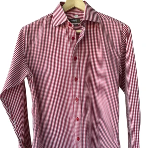 Ströms röd/vit skjorta, storlek 40 - Från Ströms herrekipering, röd- och vitrutig slim fit, storlek 40. 100% bomull. Behöver flytta reservknappen, litet fel i tyget vid armhålan, syns inte direkt när man har skjortan på sig. Precis kemtvättad. Jag säljer många skjortor i samma storlek, kolla gärna på mina övriga annonser för att skapa ett paket. Axelbredd: 45 cm Längd: 76 cm