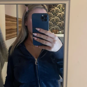 Mörkblå hoodie från Juicy Couture - Säljer en snygg mörkblå hoodie från Juicy Couture. Den har en dragkedja framtill och en mysig huva med snörning. Perfekt för en avslappnad stil. 