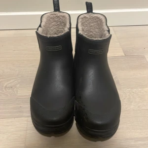 Svarta fodrade boots från Tretorn - Säljer ett par svarta boots från Tretorn med varmt foder. Perfekta för kalla dagar med sin robusta design och bekväma passform. De har en praktisk dragflik baktill för enkel påtagning.