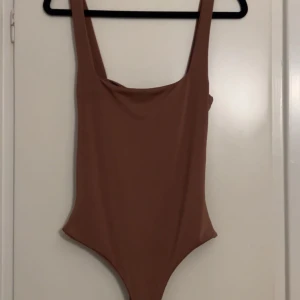 Brun body  - Snygg brun body med breda axelband och stilren design. Perfekt till jeans, kostymbyxor eller kjol. Enkel och elegant stil som passar till många tillfällen. Från Missguided. 