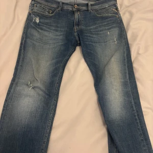 Blå jeans från Replay - Snygga blå jeans från Replay, modell Jondrill. De har en klassisk femficksdesign med slitna detaljer för en trendig look. Perfekta för en avslappnad stil.