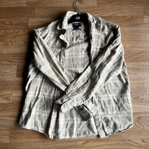 Beige rutig skjorta från Pull&Bear - Säljer en beige rutig flannelskjorta från Pull&Bear i relaxed fit. Säljer den för att jag behöver kapital och den inte längre passar in i min garderob. Inga skavanker. 