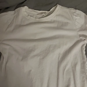 Vit t-shirt från Mango - Säljer en klassisk vit t-shirt från Mango i storlek M. T-shirten har en enkel design med rund hals och korta ärmar. Perfekt basplagg för garderoben.