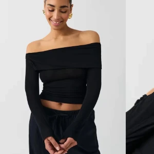 Off shoulder topp - Långärmad off shoulder topp med uppvikt kant upptill. Toppen är svart och har normallängd. Den har figurnära passform. Prislapp kvar.