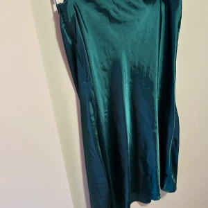 Grön midikjol - Snygg grön kjol i satin som ger en elegant look. Perfekt för speciella tillfällen med sin glänsande yta och stilrena design 🤍🤍