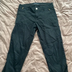 Svarta byxor från Stockh LM - Snygga svarta byxor från Stockh LM med dragkedjor på fickorna och en knappstängning fram. Byxorna har hällor för bälte och en stilren design som passar perfekt till olika tillfällen.