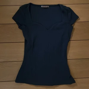 Mörkblå topp från Anna Field - Snygg mörkblå topp från Anna Field med korta ärmar och v-ringning. Toppen har en ribbad struktur som ger en stilren look. Perfekt för att matcha med både jeans och kjol.