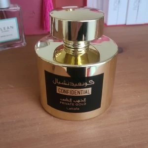 Confidential Private Gold Parfym - Elegant parfymflaska i glänsande guld med svart etikett. Flaskan har en rund form och en matchande guldfärgad kork. Perfekt för den som söker en lyxig doftupplevelse. Ordinarie pris 260kr.