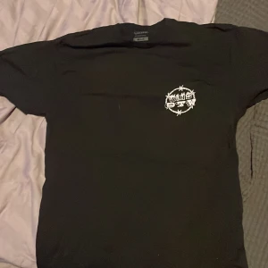 Svart t-shirt från Vans - Säljer en svart t-shirt från Vans med tryck på både fram- och baksidan. Framsidan har en liten logga medan baksidan har ett stort, färgglatt tryck med text och grafiska element. Perfekt för en avslappnad stil. Använd cirka 2 gånger inga defekter! Hör av er om frågor:)