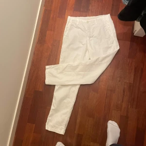 Vita byxor från Massimo Dutti - Snygga vita byxor från Massimo Dutti i en tapered fit. Perfekta för en stilren look. Byxorna har knappar och är tillverkade i ett bekvämt material.