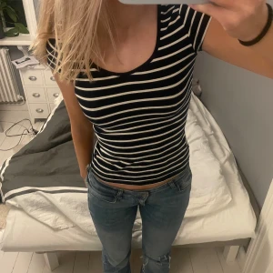 Svart och vit randig topp - Säljer en svart och vit randig topp med korta ärmar. Toppen har en tight passform och är perfekt för en avslappnad stil. Den är gjord i ett mjukt och bekvämt material.