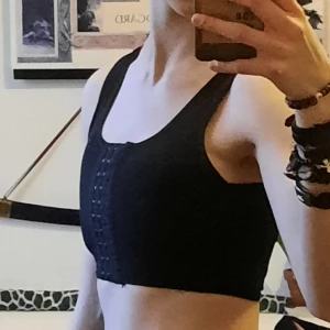 Svart kort binder - Säljer en svart binder med anpassningsbar hakknäppning framtill och vid axlarna. Helt ärligt den bästa bindern jag haft, tyvärr har den dock en liten töjning vid ena armhålan (råkade köra den i tvättmaskin), men det syns inte under en t shirt! Jätteskönt att den är anpassningsbar, och går ovanligt smidigt att ta av och på. Vet inte storlek, men den passar mig och jag har XS på storleksguiden för spectrum så kolla in den:)