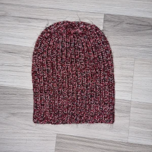 Röd och svart ribbad mössa - Snygg ribbad mössa i röd och svart färgkombination. Perfekt för kyliga dagar med sin stickade design som ger både stil och värme. Mössan är hemmastickade.