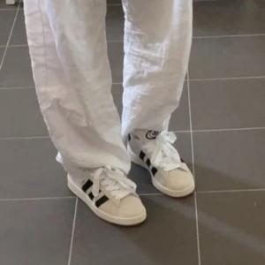 Adidas Campus sneakers  - Säljer ett par klassiska Adidas Campus sneakers i ljus beige med svarta detaljer. Slitage vid hällen på båda men går att laga enkelt. Små missfärgningar frame vid tårna annars väldigt fint skick på utsidan