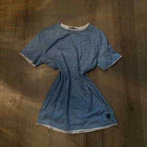 Blå t-shirt från S.C.W. - Säljer en blå t-shirt från S.C.W. med vita kanter. T-shirten har en normal passform och är kortärmad, perfekt för en avslappnad stil. Tillverkad i ett mjukt material för extra komfort.