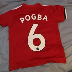 Röd Manchester United fotbollströja - Säljer en röd Manchester United fotbollströja från Adidas med Pogba