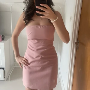 Rosa axelbandslös klänning - Säljer en söt rosa axelbandslös klänning i kort modell från Missguided. Den är använd endast en gång och är i jätte fint skick🩷