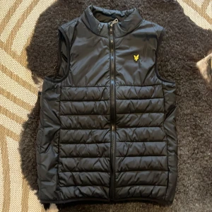 Svart dunväst från Lyle & Scott - Säljer min riktigt snygga lyle scott väst. Den är perfekt nu när våren börjar glida in😊. Västen är kär på kids brand store och orginal pris är 800 kr. Pris kan även alltid snackas om det är så!! MVH Elliot