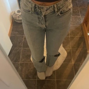 Ljusblå jeans med slitna detaljer från bikbok - Säljer ett par ljusblå jeans med hög midja och slitna knän från bikbok. De har en straight passform och klassisk femficksdesign. Perfekta för en avslappnad stil.