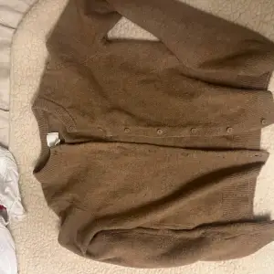 Säljer en mysig brun kofta från H&M. Den har långa ärmar och knappar framtill. Perfekt för kyliga dagar och passar till det mesta i garderoben.