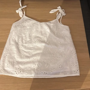 Vit blommig linnetopp från Shein - Säljer en söt vit linnetopp från Shein med blommigt broderi. Toppen har knytband på axlarna och är perfekt för varma sommardagar. Passar bra till både jeans och kjol. 🌸