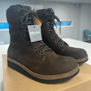 Bruna boots från New Feet - Damkänga med snörning och blixtlås.  Picosfoder med vattenavvisande membran. Yttersida EVA med medium vippfunktion. Hällyft 28mm - fall 14mm. Löstagbar 6mm stöddämpande innersula. Storlek 37. Helt nya med lapp och orginalkartong. Märke New Feet. Medicinska och fotriktiga skor gjorda för diabetiker och reumatiker. Nypris 2200kr