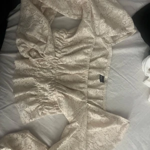 Beige spetsblus - Säljer en romantisk beige spetsblus med elastisk midja och långa ärmar. Blusen har ett vackert spetsmönster och är perfekt för en elegant look. Passar bra till både jeans och kjol. Den är knappt använd.